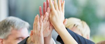 Photo of severals adults' hands high fiving.