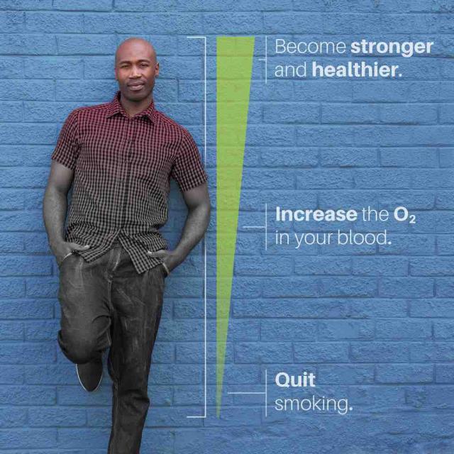 Man standing against wall next to line depicting increase in oxygen and strength after quitting smoking with text at the bottom saying "quit smoking", text in the middle saying "increase the O2 in your blood" and text at the top saying "become stronger and healthier"